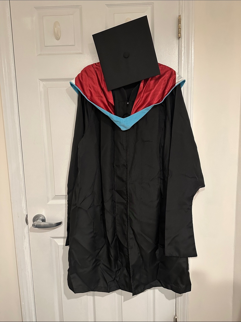 Black Graduation Gown with Red and Light Blue Hood and Mortarboard